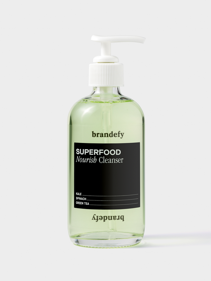 Clear pump bottle of Brandefy Superfood Nourish Cleanser with pale green liquid inside.