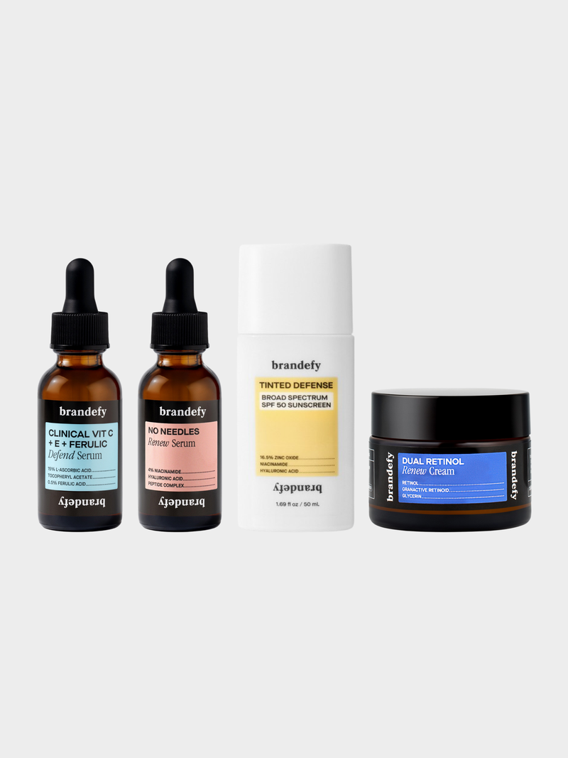 The 2 Minute Method bundle: two amber dropper bottles labelled Clinical Vit C + E + Ferulic Defend Serum and No Needles Renew Serum, a white and yellow bottle labelled Tinted Defense Broad Spectrum SPF 50 Sunscreen, and an amber glass jar labelled Dual Retinol Renew Cream.