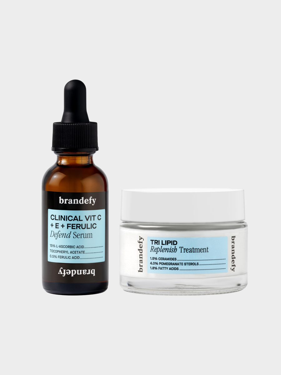 The Defend Derm Duo: the amber Clinical Vit C + E + Ferulic Defend Serum dropper bottle standing beside the white-lidded Tri Lipid Replenish Treatment jar, on a plain grey background.