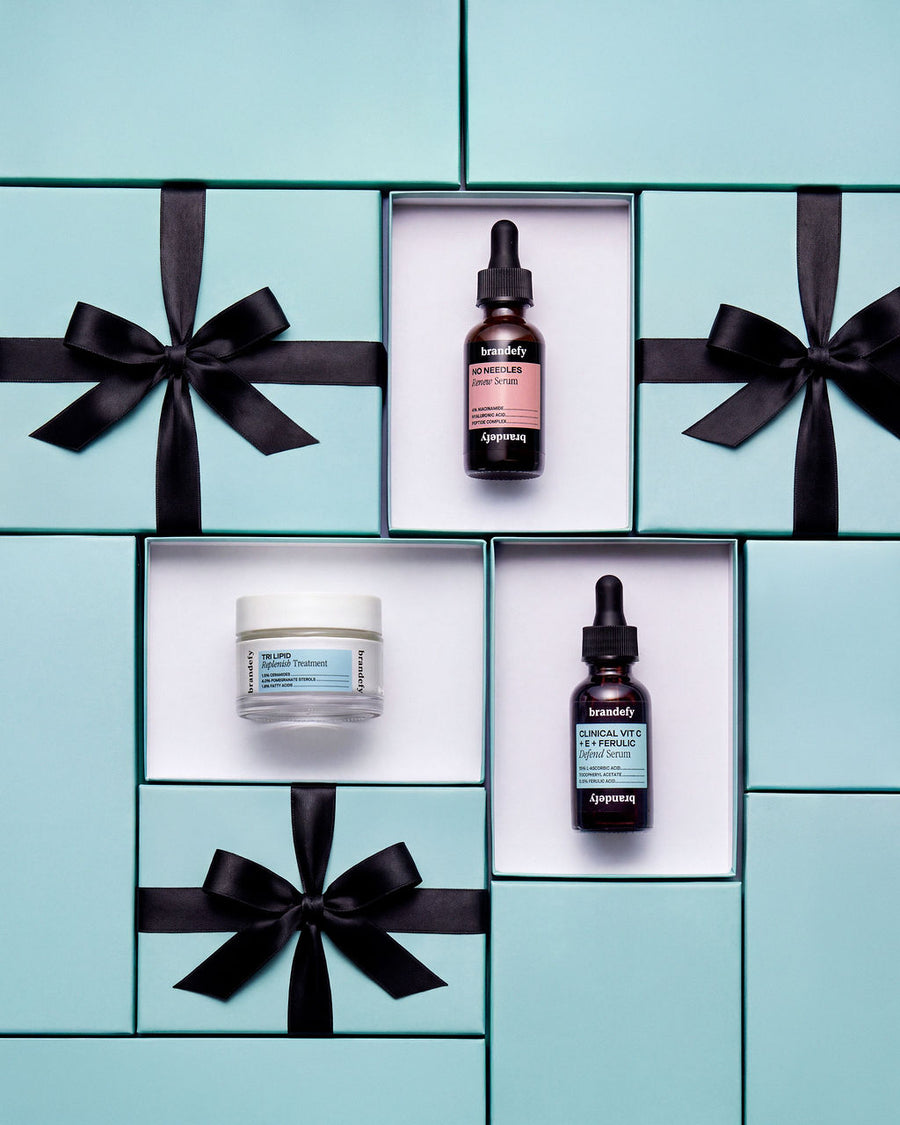 The three Bestsellers Trio products, each in an open pale-blue gift box tied with black satin ribbon.